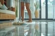 Barefooted individual tidying up the house by mopping the tile floor with a white mop in a contemporary setting