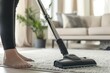 The image depicts a neat and orderly living room being vacuumed by a person, focusing on home cleanliness