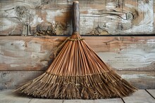 An Old-fashioned Broom Stands Against A Rustic Wood Paneled Wall, Embodying Timeless Cleanliness