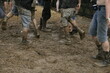 A group of people are walking through a muddy field