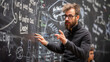 © sommersby - A man is standing in front of a blackboard covered with writing. He appears to be studying or teaching in a classroom setting