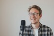 A handsome smiling man with glasses and headphones at a podcasting studio mic