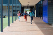 © wavebreak3 - Biracial boy and girl run joyfully with another child through a school corridor with copy space