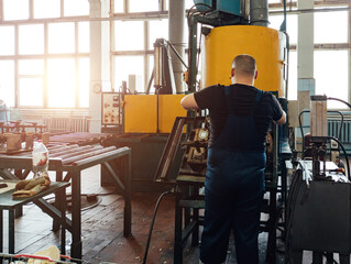 Wall Mural - Worker operates plastic stamping forming machine in workshop