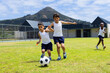 Biracial and African American boys play soccer outdoors at school, with a mountain in the background