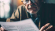 Photo of a senior reviewing his life insurance policy with a close up on the document and his reading glasses underscoring the significance of insurance in retirement planning