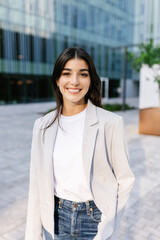vertical portrait of young happy businesswoman standing over modern company office building