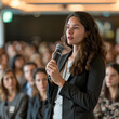 © jirasin - Female manager asking a question, Female manager asking a question from audience while participating in business seminar at convention center