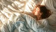 brunette woman sleeping snuggled comfy cozy bed pillow sheets comforter morning light casting on face and bed 