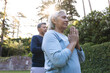 © Wavebreak Media - Senior biracial woman and man meditate outdoors at home, sunlight filtering through trees