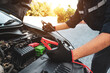 Hand car mechanic holding car booster cables for jump start car for empty battery dead and low voltage power problem or fix service maintenance accident assistance technician and energy charge.