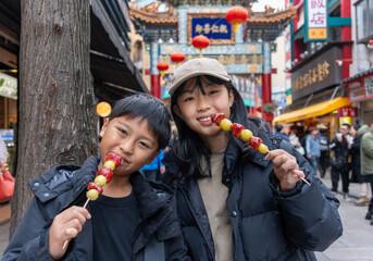 Wall Mural - 横浜中華街でいちご飴を食べる日本人の男の子と女の子