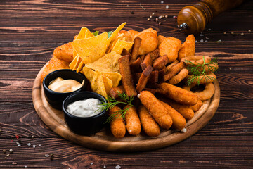 Wall Mural - Fastfood fried chicken fillet, crispy onion rings, cheese sticks, garlic croutons, nachos, sauces and greens.