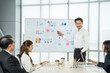 © Bavorndej - Man presenting statistical data to attentive colleagues during a business strategy meeting in a modern office setting.