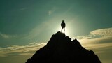 Fototapeta Natura - silhouette of a man at the top of the mountain against the sky