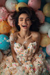 © J S - Birthday card of a happy laughing beautiful young brunette woman dressed in birthday cake cream icing on background with colorful balloons