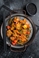 Canvas Print - Chicken meat in sweet and sour sauce in a steel tray. Black background. Top view