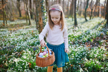 Wall Mural - Five year old girl playing egg hunt on Easter