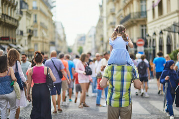Wall Mural - Father holding daughter on shoulders and walking on a street of Paris, France