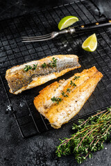 Wall Mural - Grilled sea bass fillet with lime and thyme. Black background. Top view