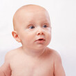 © T. Rose/peopleimages.com - Young, cute and face of baby on a white background for child development, youth and growth. Curious, facial expression and closeup of isolated newborn for childhood, wellness and adorable in studio