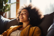 Happy African American lady relaxing on the couch at home - smiling girl enjoying a day off lying on the couch - healthy lifestyle, good mood people and new home concepts