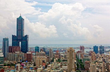 Wall Mural - Cityscape of Kaohsiung Downtown, a vibrant seaport city in Southern Taiwan, with the landmark 85 Sky Tower standing out among modern buildings and ships parking in the harbor under cloudy sunny sky