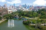 Fototapeta Uliczki - Aerial scenery of Downtown Taichung, a vibrant metropolis in central Taiwan, with modern skyscrapers in background & a rainbow fountain in a pond surrounded by green forests in a park under sunny sky