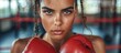 © FryArt - A focused Hispanic female boxer with freckles on her face wearing boxing gloves.