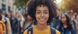A black woman college student with curly hair wearing a yellow shirt.