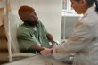 © Seventyfour - Portrait of African American man receiving chemotherapy treatment in procedure room at clinic behind glass copy space