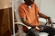 © Seventyfour - Cropped shot of Black adult man getting IV drip treatment in clinic sitting in chair with medical tubes copy space
