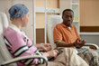 © Seventyfour - Portrait of Black adult man talking to another patient during chemotherapy treatment in clinic