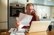 © Marko Geber - Stressed man going over bills at home