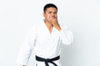 Young Ecuadorian man doing karate isolated on white background happy and smiling covering mouth with hand