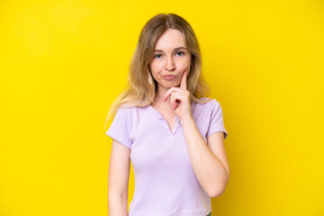 Wall Mural - Blonde English young girl isolated on yellow background and thinking