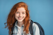 Young pretty Redhead girl over colorful background with a student backpack