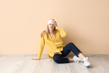 Poster - Young woman with brain concussion sitting near beige wall