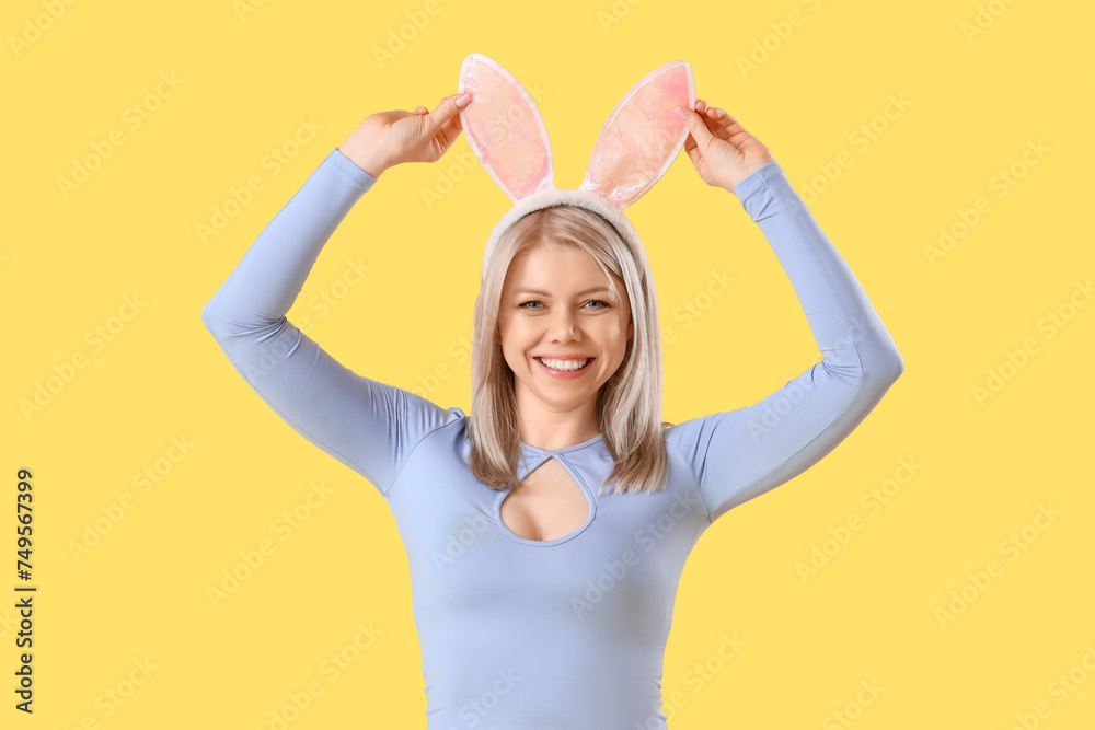 Beautiful woman in bunny ears on yellow background. Easter celebration