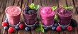 Three glasses filled with smoothie made from fresh berries such as blackberry, raspberry, and blueberry, garnished with mint leaves, placed on a rustic wooden table.