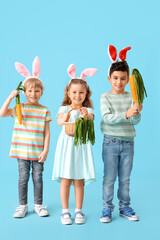 Poster - Cute little children in bunny ears with toys carrots on blue background. Easter celebration