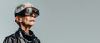 A senior woman with silver hair presents a visionary sight, her gaze directed upward through futuristic VR glasses, set against a minimalist gray background.