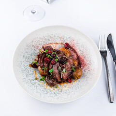 Canvas Print - Veal cheeks with smashed potatoes and porto sauce with cranberries and microgreens with a glass of wine.