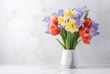 Fototapeta Tulipany - A colorful bouquet of tulips and crocuses in a marble vase on a white marble background.
