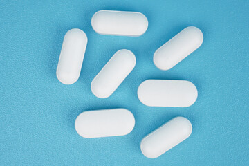 Long shaped white medical tablet isolated on blue background