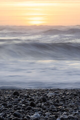 Wall Mural - The ocean is calm and the sun is setting, creating a serene