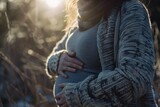 Fototapeta  - A close up of a pregnant woman cradling her belly with gentle hands against a backdrop of soft natural light embodying the beauty of motherhood