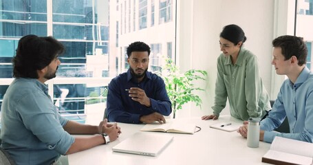 Wall Mural - Multinational workmates listening team leader express opinion, talk about new task, share issue solutions, make speech at group briefing in modern conference room. Leadership, seminar event for staff