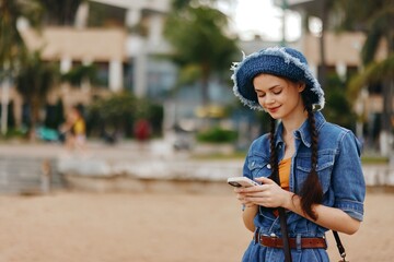 Wall Mural - Happy Young Woman Holding Smartphone and Smiling in the Park