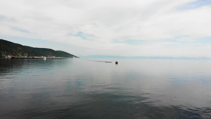 Wall Mural - A boat on Lake Baikal ferries tourists from the village of Listvyanka to the port of Baikal on a summer evening.